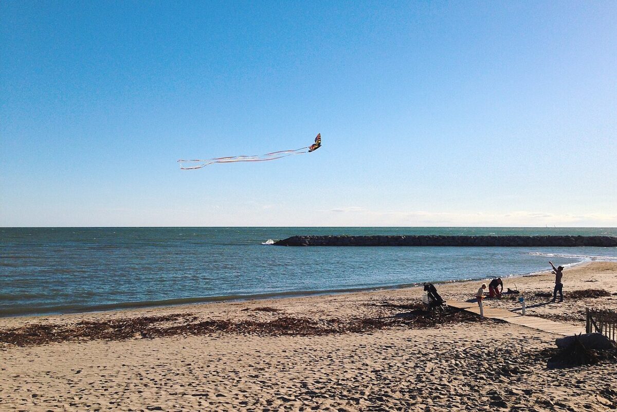 Cerf-volant au-dessus de la plage de La Grande-Motte par vent soutenu et ciel dégagé, plage presque déserte