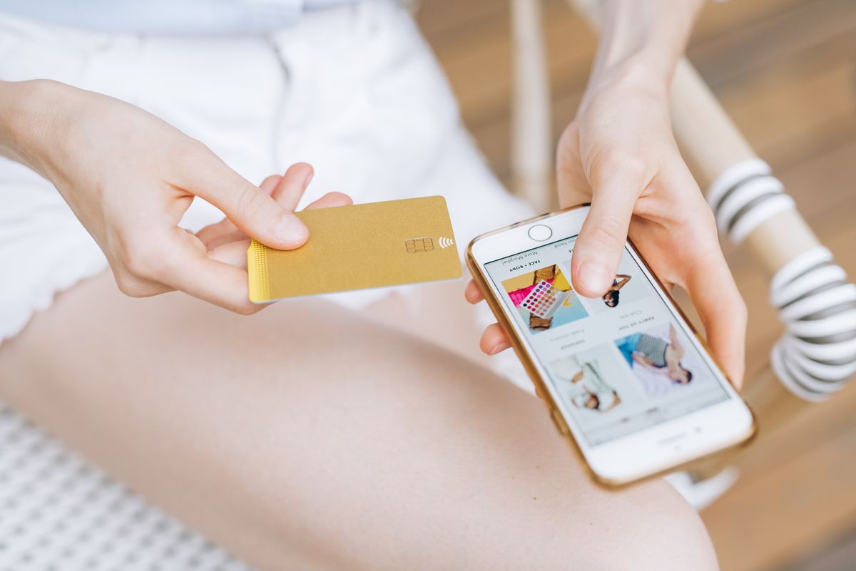 Carte bancaire dorée et smartphone lors d'un paiement en ligne, l'achat du voyage déclenchant l'assurance de la carte Gold