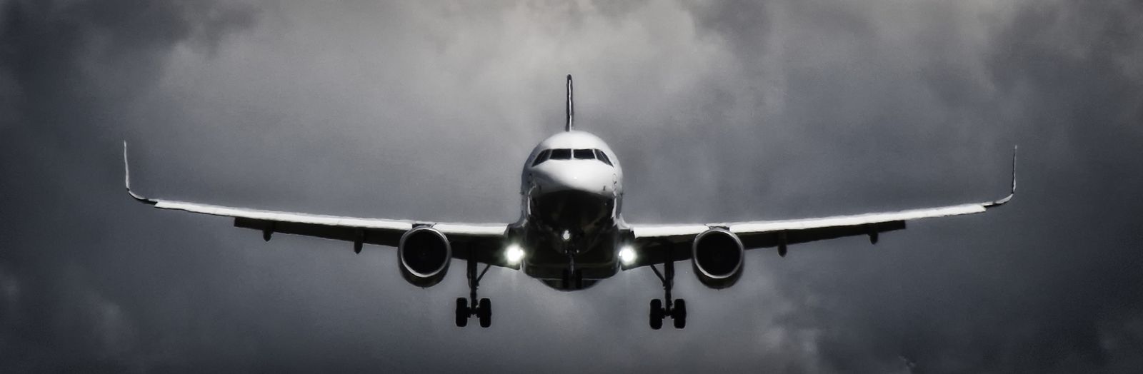Avion en approche d'atterrissage sous un ciel orageux en noir et blanc