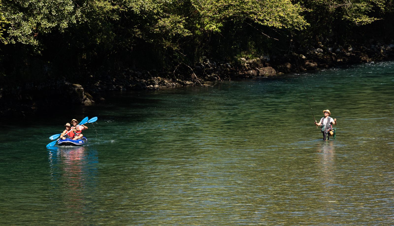 Personnes pratiquant le kayak et la pêche sur une rivière pittoresque.