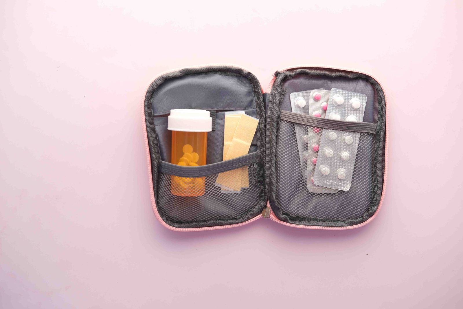 Trousse de pharmacie ouverte avec flacon, plaquettes et pansements.