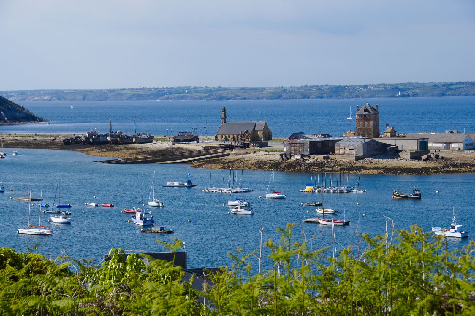 Port côtier avec bateaux amarrés et mer bleue.