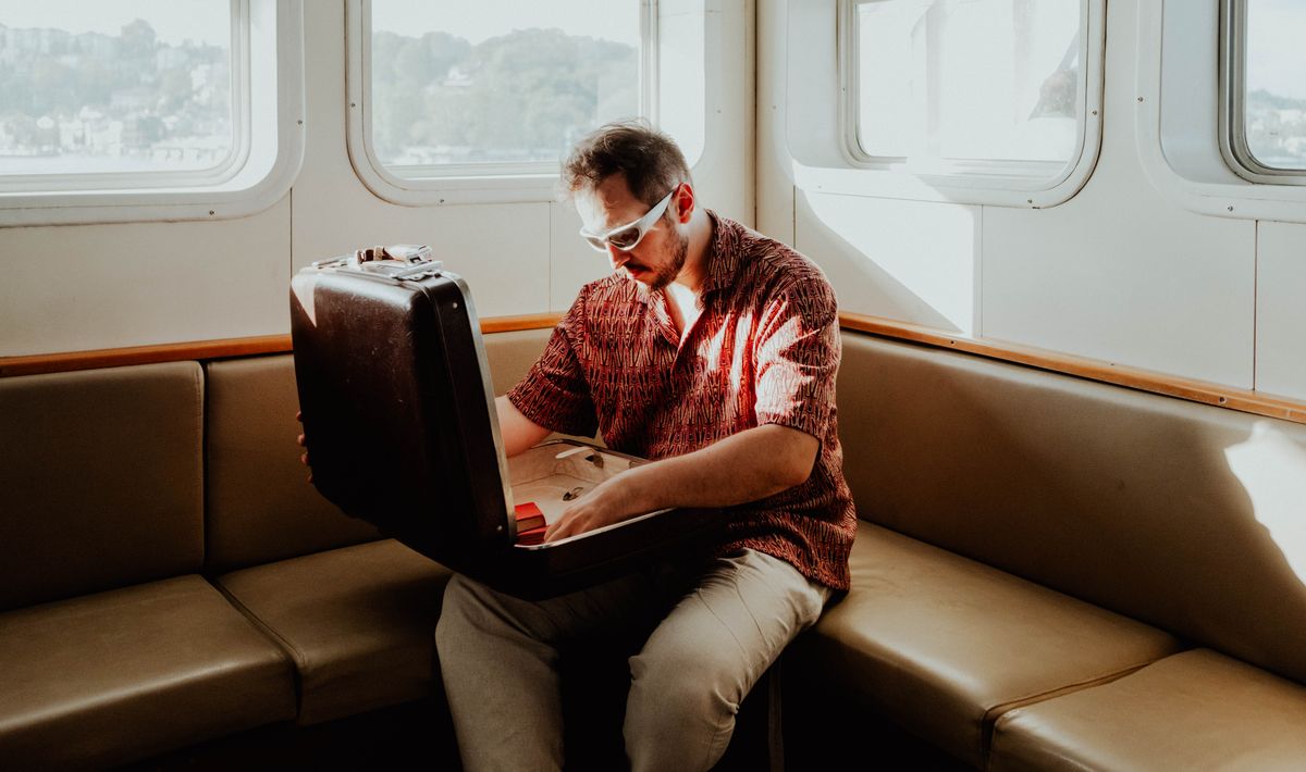 Homme avec lunettes de soleil ouvrant une valise dans une cabine de train.