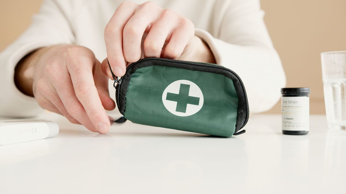 Mains tenant une trousse de secours sur une table avec bandelettes de test.