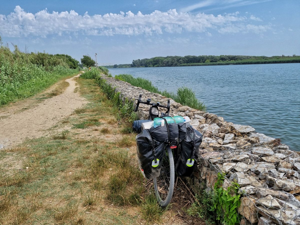 Vélo avec sacoches sur un chemin rural près d'une rivière.