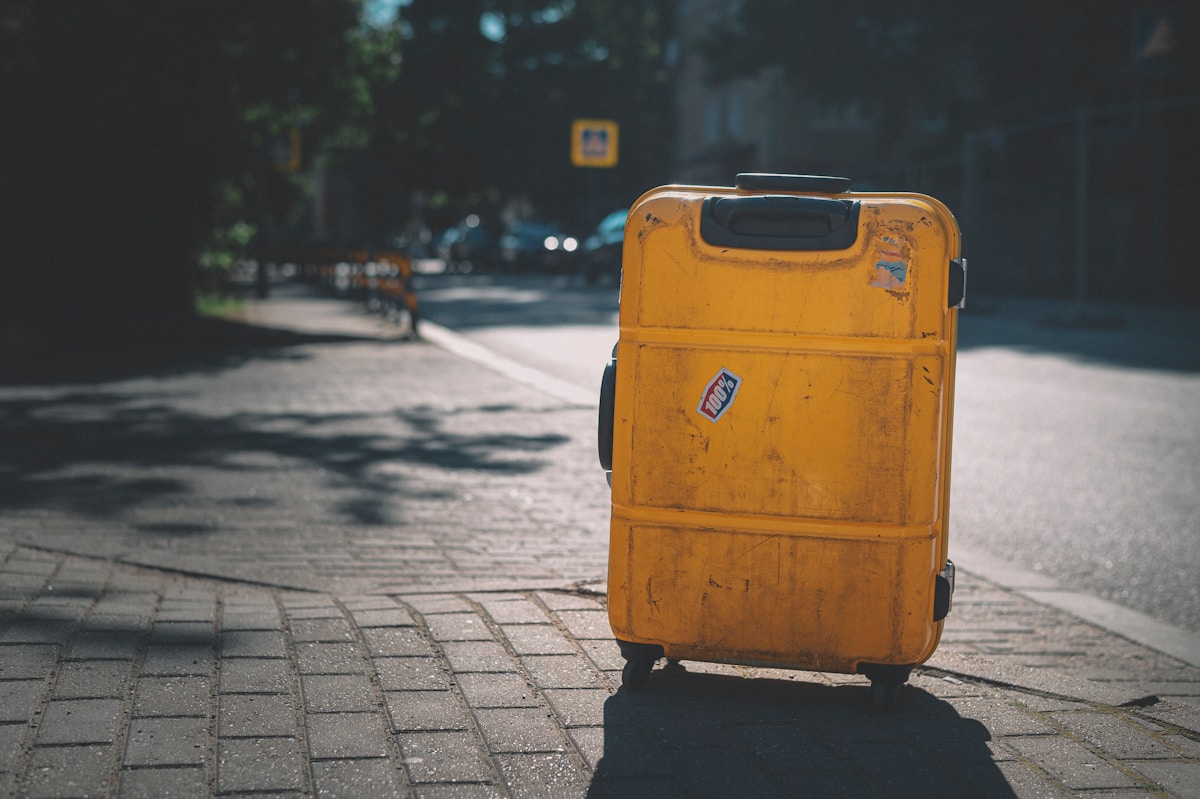 Poubelle jaune en plastique sur un trottoir en journée.