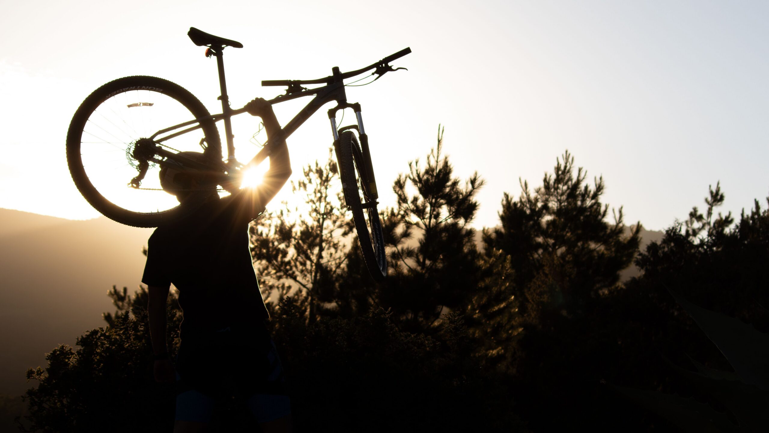 Cycliste soulevant son VTT au coucher du soleil