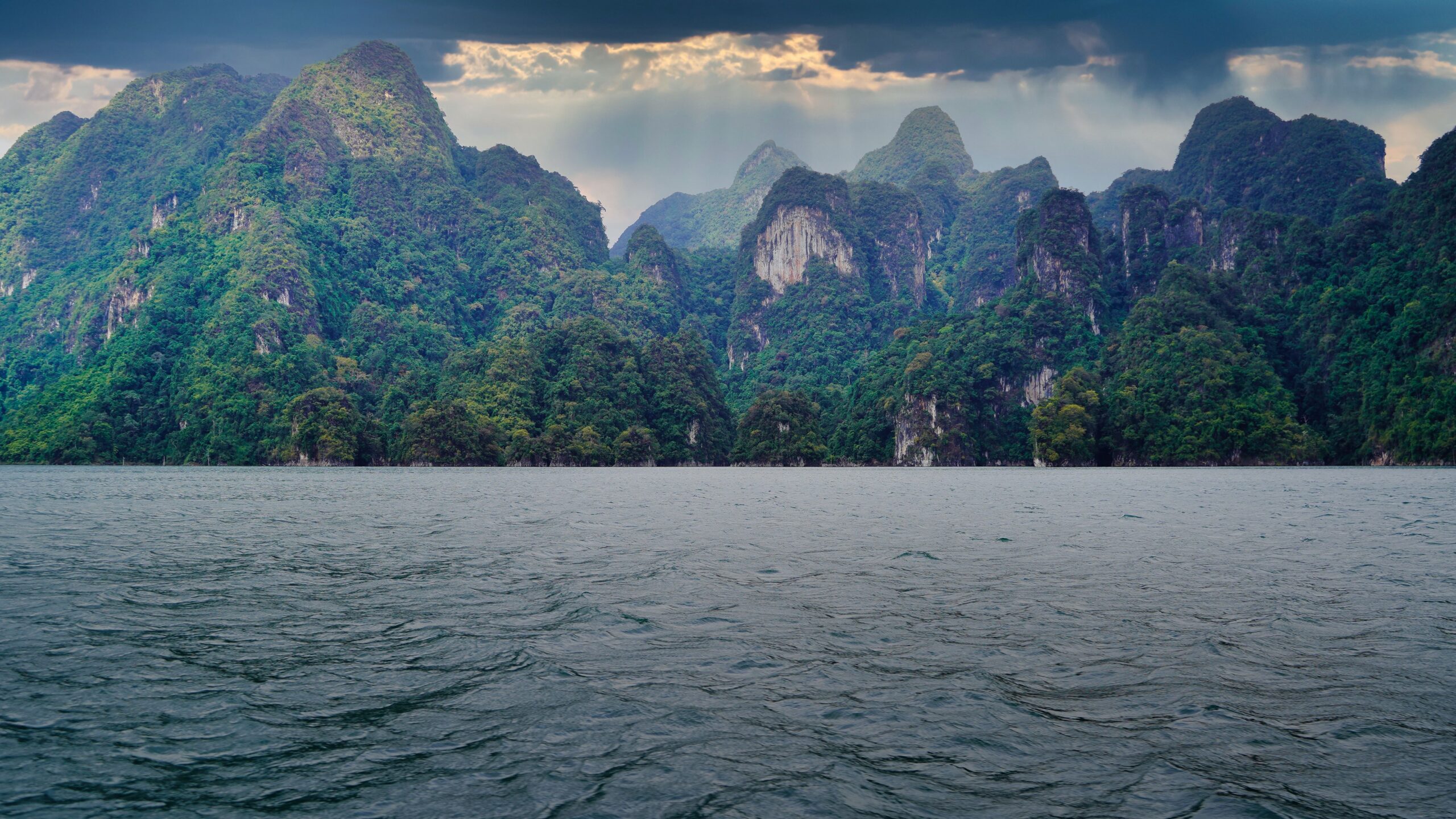 Paysage de karsts calcaires et d'eau à Surat Thani, Thaïlande, sous un ciel nuageux annonçant la mousson.