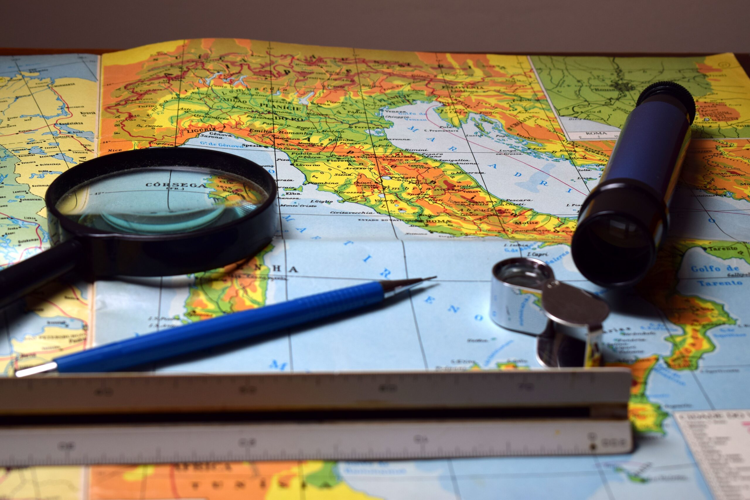 Loupe, règle et crayon posés sur une carte du monde pour préparer un itinéraire.