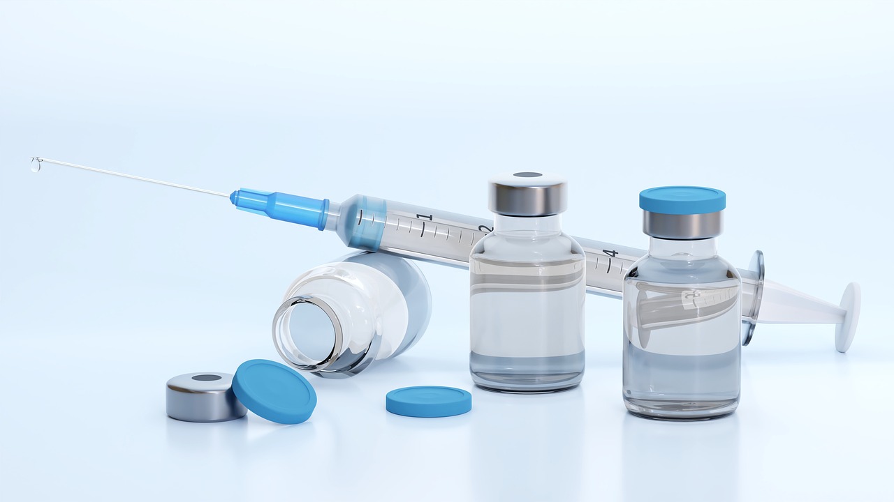 Seringue et flacons de vaccin posés sur une surface claire.
